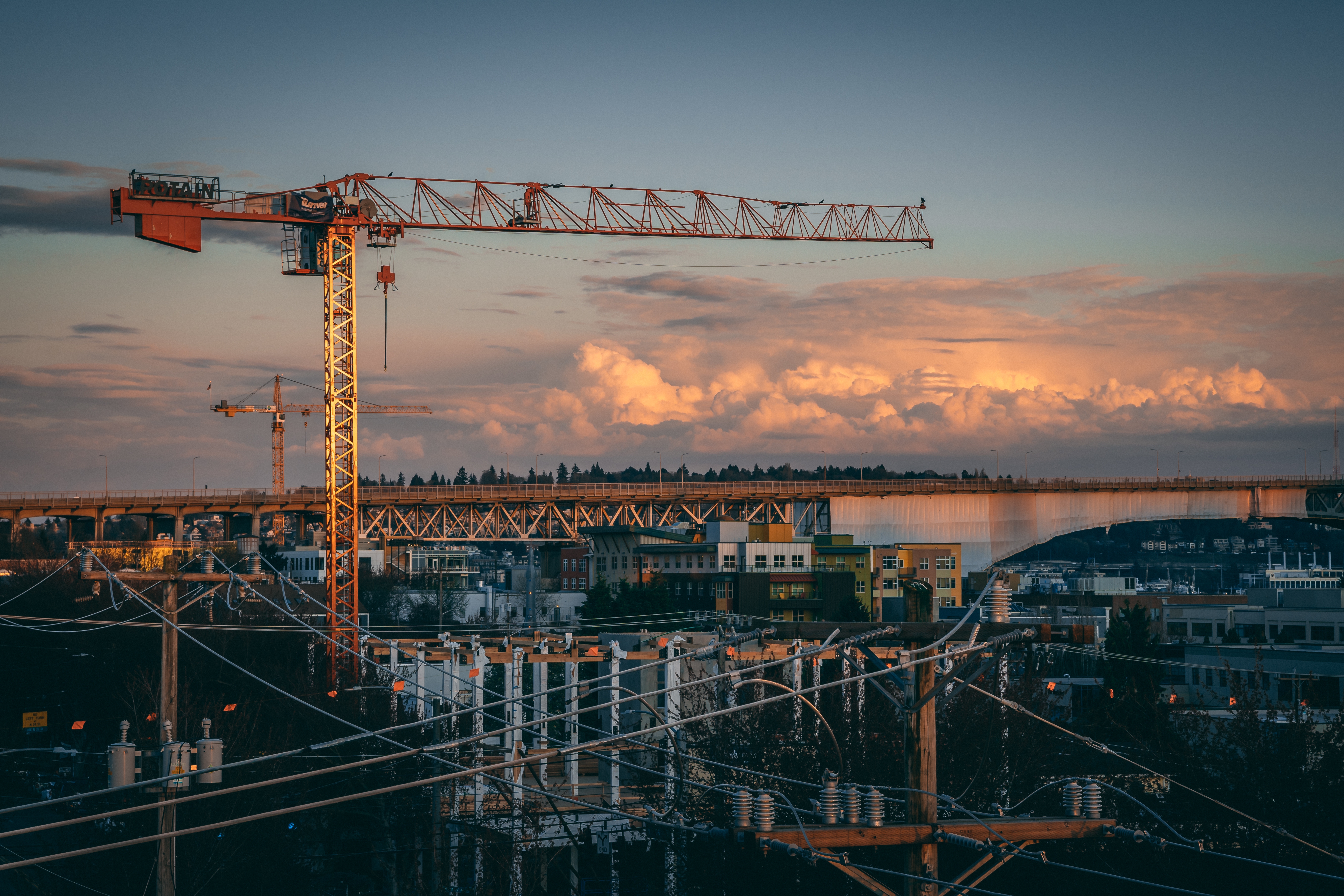 Construction crane at sunset with cityscape background